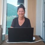 Xenia sitzt vor dem Laptop auf dem Balkon
